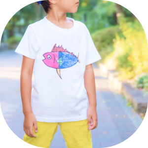 自分が描いた魚の絵のTシャツを着る子ども