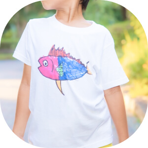 自分が描いた魚の絵のTシャツを着る子ども