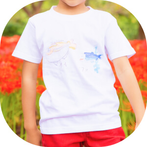 自分が描いた魚の絵のTシャツを着る子ども